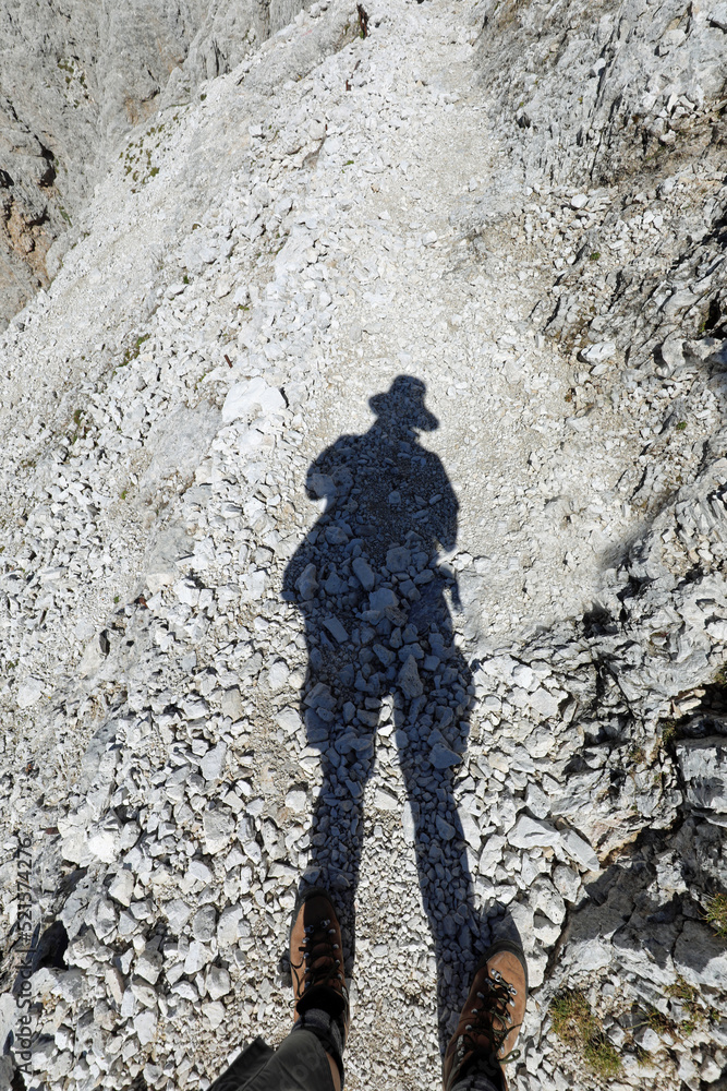 explorer with hat and his shadow on the stony path