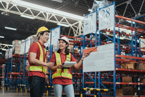 Warehouse Workers Checking Stock with digital Tablet in Logistic center. Asian Female manager and Male Worker wearing Hard hat talking about shipment in storehouse, Working in Distribution Center.