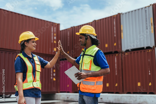 Industrial Engineer giving high five to colleague in Logistic center. Asian Indian workers wearing safety vests to working about shipment in Container terminal, Working in Storage Distribution Center.