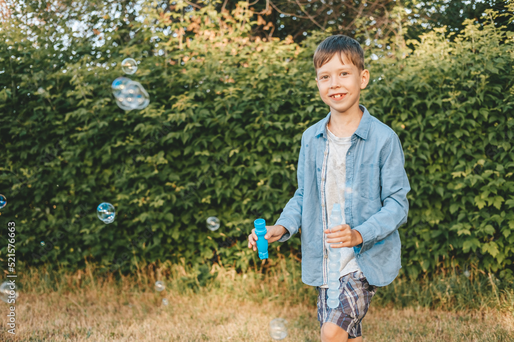 A boy is playing with soap bubbles in a summer park, Among the greenery.