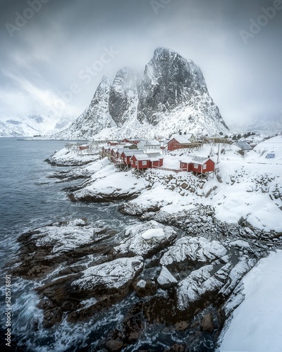 Snowy mountain at the shore with red wooden houses photo