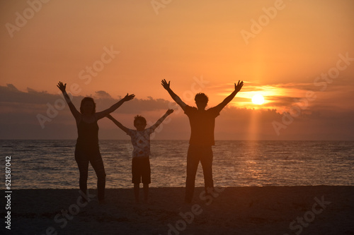 Silhouette of family watching sunset at beach. Happy family enjoy on sea on summer vacation