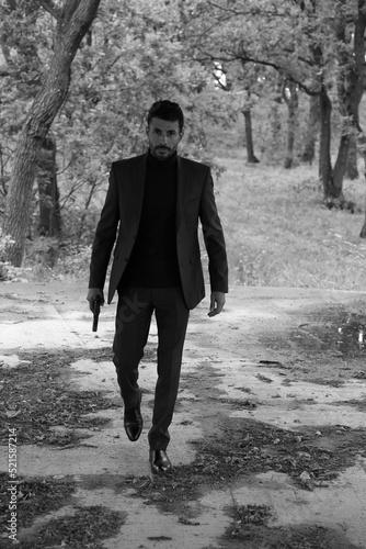 Detective with a gun in the forest in black and white