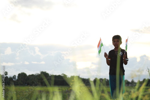 
little Boy holding tri colour national Indian flag in the nature & waving flag in the air. Independence Day - Holiday and Republic Day