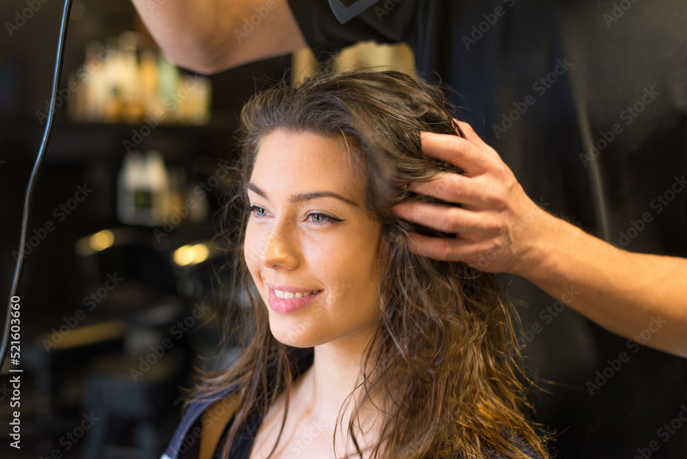 Fototapeta premium Young woman getting new hairstyle from hairdresser in the modern hair salon