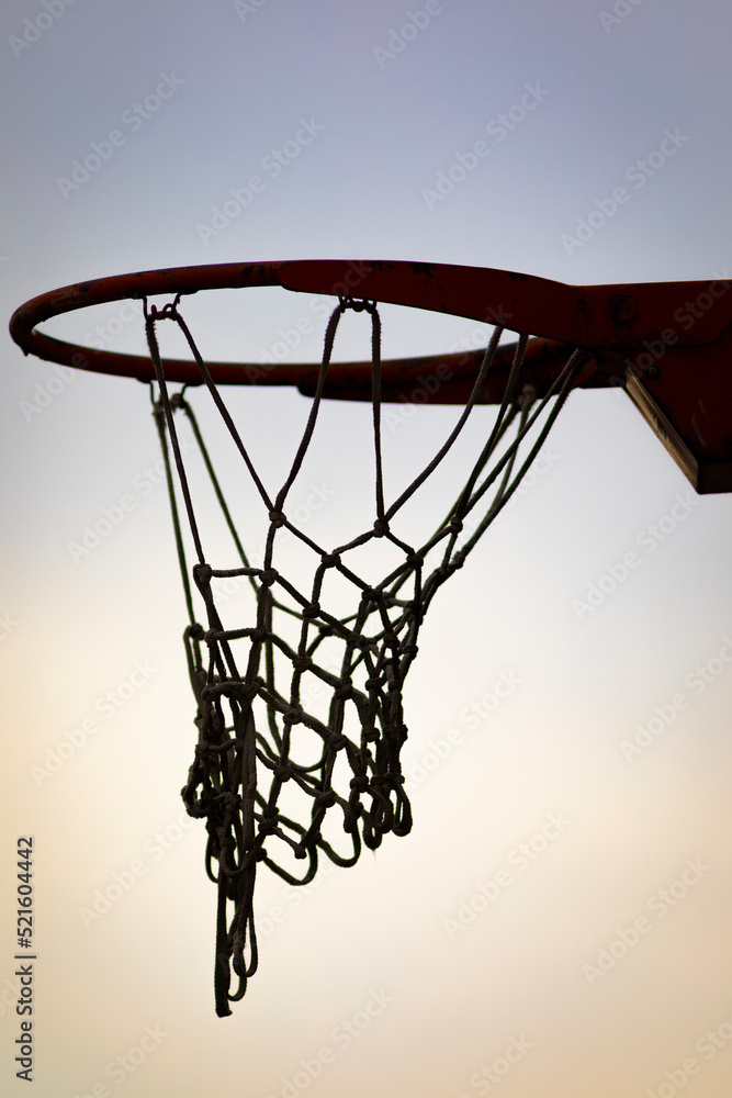 Silueta de una canasta de baloncesto (basket, basketball) durante un atardecer de verano (outdoor al aire libre)