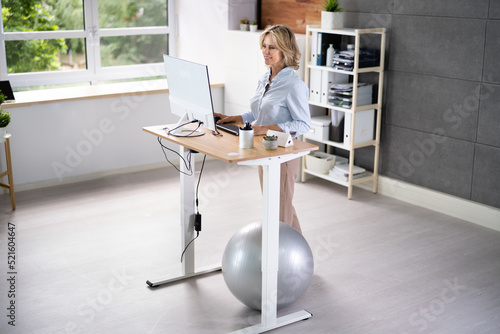 Woman Using Adjustable Height Standing Desk In Office © Andrey Popov