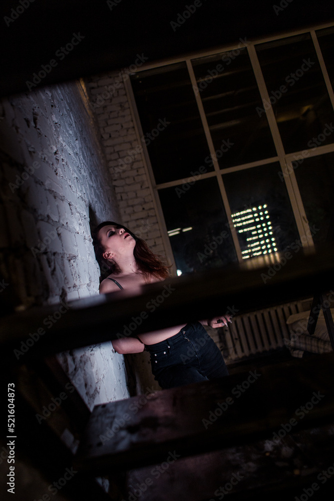 Fototapeta premium Sexy girl dance on front of spot light wall with smoke