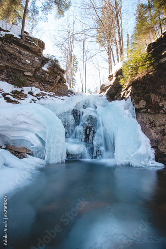 Frozen waterfall under snow cover in Wisla Czarne - Rodla Cascades in the Polish Beskydy Mountains, Poland. Wild nature and its beauty photo