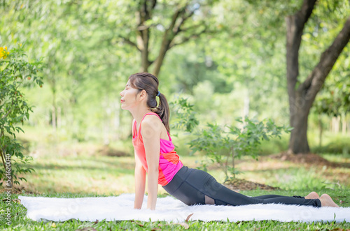 Young woman doing exercises in yoga pose in the park, Side view of slim sportswoman doing stretching exercise at summer green parks © JU.STOCKER