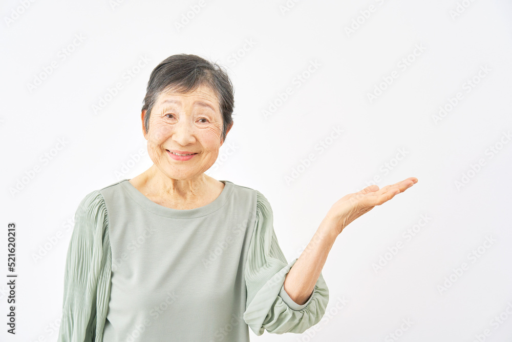 白バックで右を掌で指すシニア女性