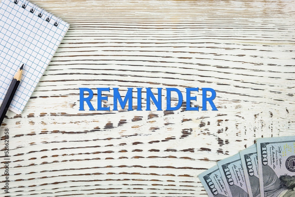 Naklejka premium REMINDER - word (text) and dollars on a white wooden table, notebook, notepad. Business concept: buying, selling, commerce (copy space).