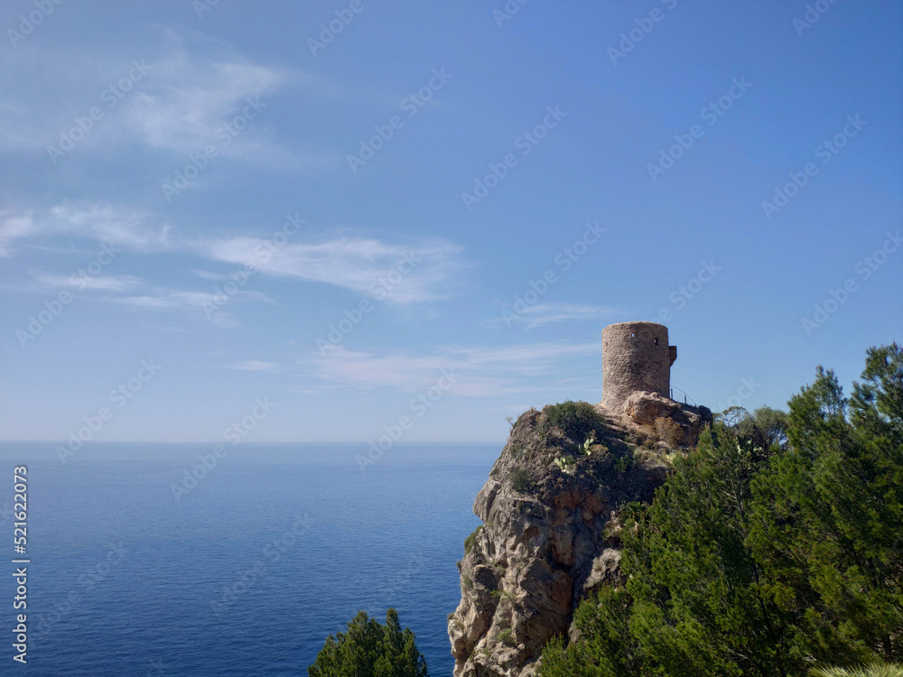 Torre del Verger watchtower on a cliff in Mallorca, Spain. Blue sea background
