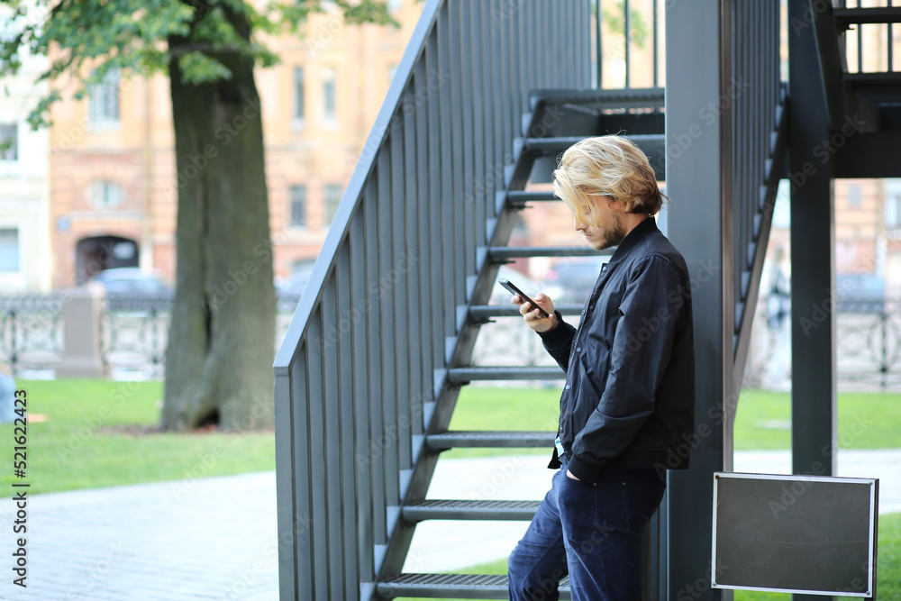 Lifestyle portrait of young man using a smartphone outdoors. Lifestyle portrait of young man using a smartphone outdoors.