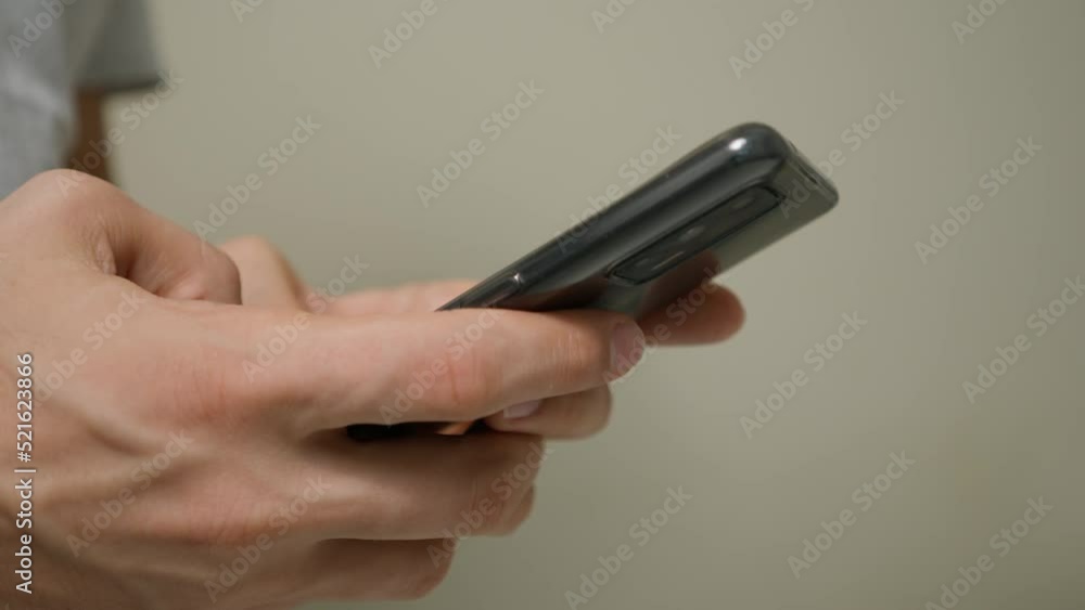 Male adult typing a message on smartphone side view close up