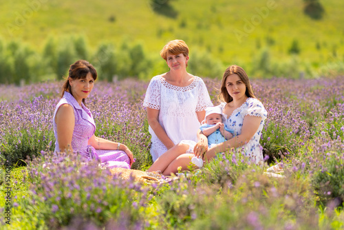 Three women sitting amongst lavender with a small baby boy © kolotype