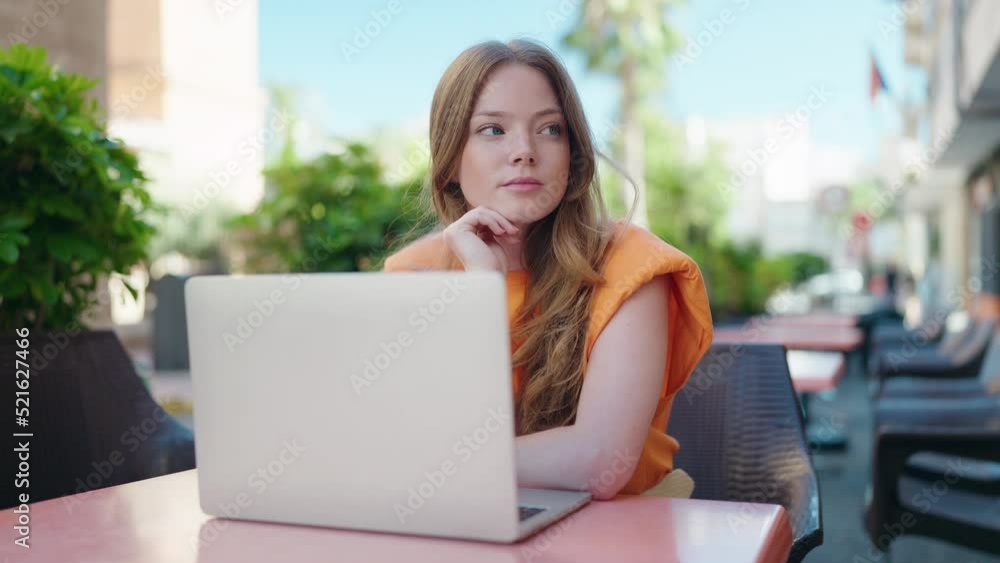 Young woman using laptop with doubt expression at coffee shop terrace Young woman using laptop with doubt expression at coffee shop terrace