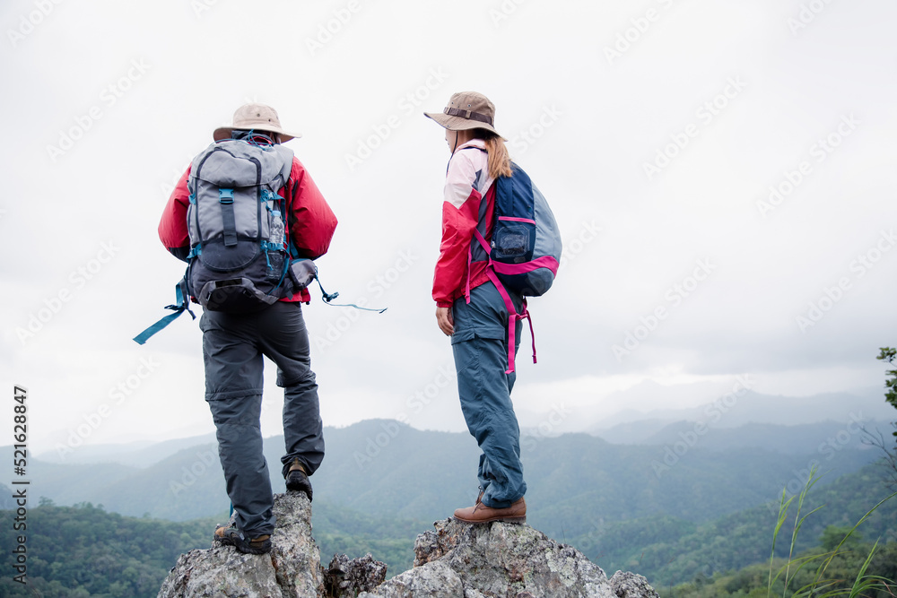 Young tourist couple watching spectacular mountain scenery in high mountains. man and woman hiker on top rock. A couple of travelers in love. People greet the dawn. Lovers travel. Copy space