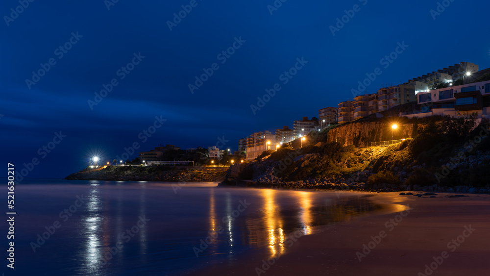 view of a coastal town at night with reflections in the water