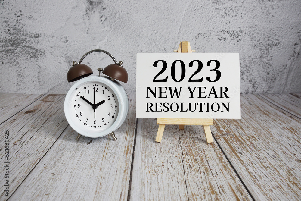 2023 New Year Resolution text message and alarm clock on wooden background 2023 New Year Resolution text message and alarm clock on wooden background