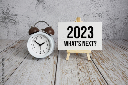 2023 What's Next? text message and alarm clock on wooden background