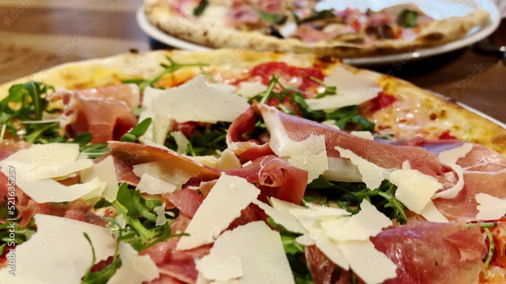 Prosciutto pizza with parmesan cheese and arugula leaves. Tasty Italian pizza - food and drink. Close up shot. Prosciutto pizza with parmesan cheese and arugula leaves. Tasty Italian pizza - food and drink. Close up shot.