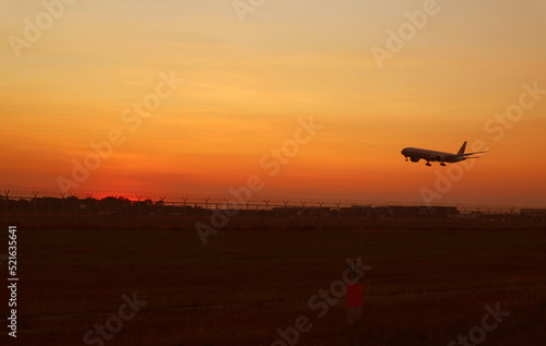 Silhouette of an airplane taking off up to golden sunrise sky