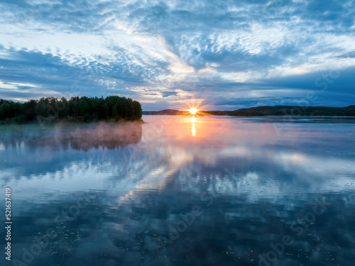 Aerial view of sunset over calm lake during midnight sun in Overtornea, Sweden.