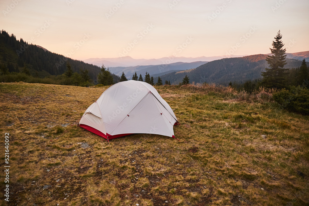 White tent in meadow with view of Mountain range. Carpathian Mountain, Ukraine. Walking and hiking trails in Marmaros ridge. Camping in  Carpathian Mountains in autumn
