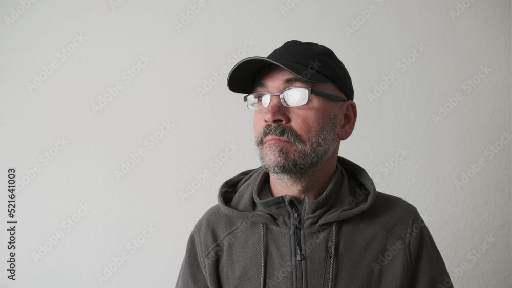 Bearded man in a cap and glasses on a white background in the studio looking at the camera and wonder Bearded man in a cap and glasses on a white background in the studio looking at the camera and wonder