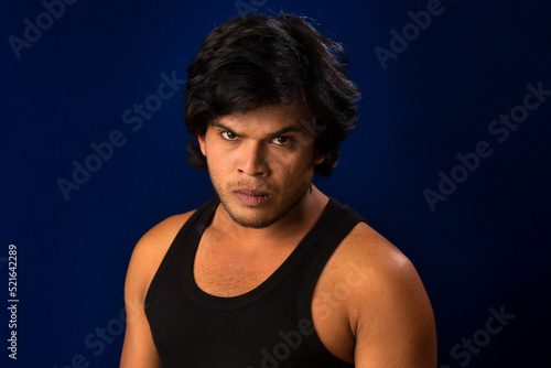 Portrait of a young man posing and showing his muscular body. The concept of a healthy lifestyle on blue background.