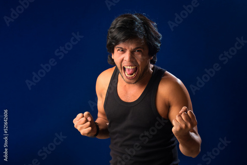 Portrait of a young man posing and showing his muscular body. The concept of a healthy lifestyle on blue background.