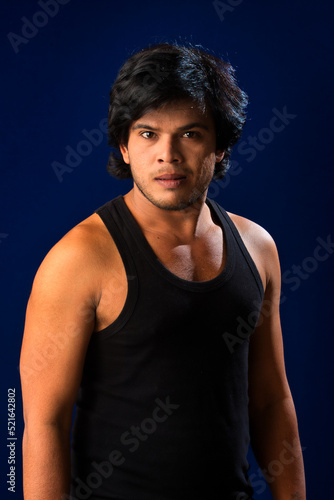 Portrait of a young man posing and showing his muscular body. The concept of a healthy lifestyle on blue background. © Dip Photography