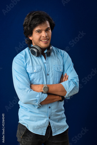 Portrait of a handsome young man enjoying music on headphones on blue background.