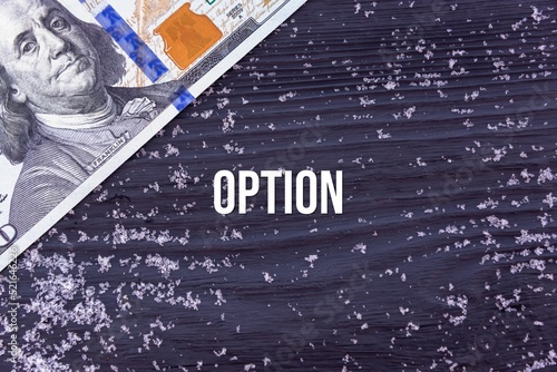 OPTION - word (text) on a dark wooden background, money, dollars and snow. Business concept (copy space).