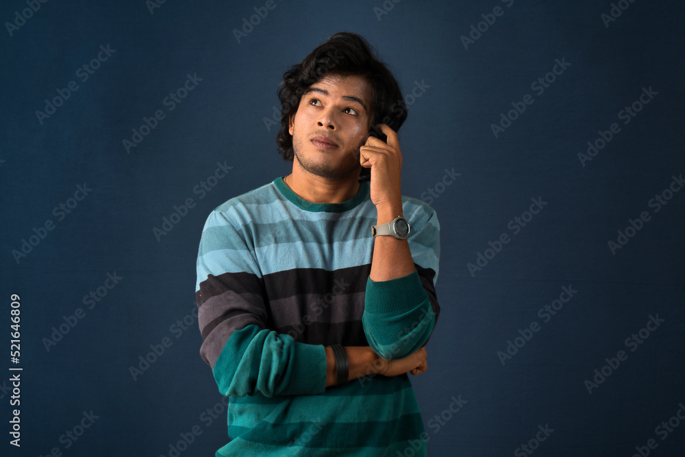 Portrait of a young man thinking on a dark background