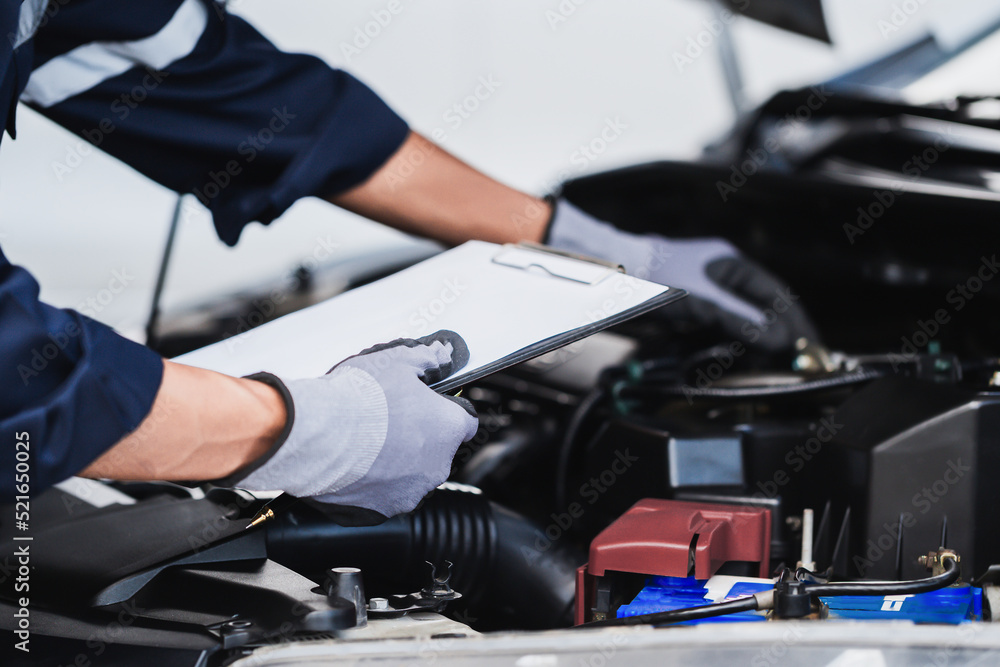 Professional mechanic working on the engine of the car in the garage. Car repair service. Professional mechanic working on the engine of the car in the garage. Car repair service.