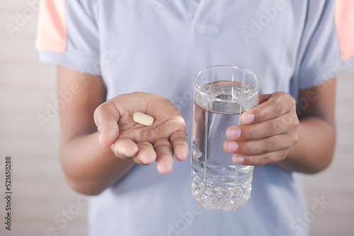 Canvastavla young man holding pills and glass of water with copy space