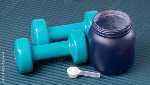 Sports nutrition and dumbbells on the mat for training