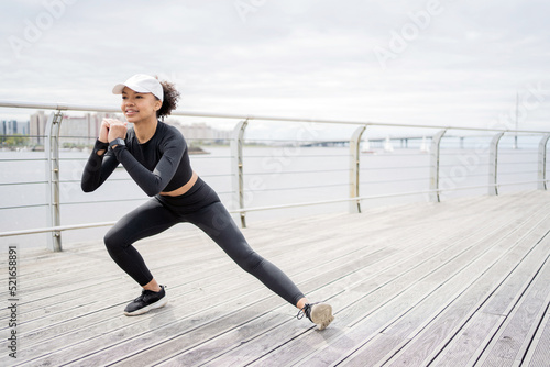A young female athlete does active fitness exercises with yoga elements, lifestyle, uses a fitness watch and a tracker to measure her pulse
