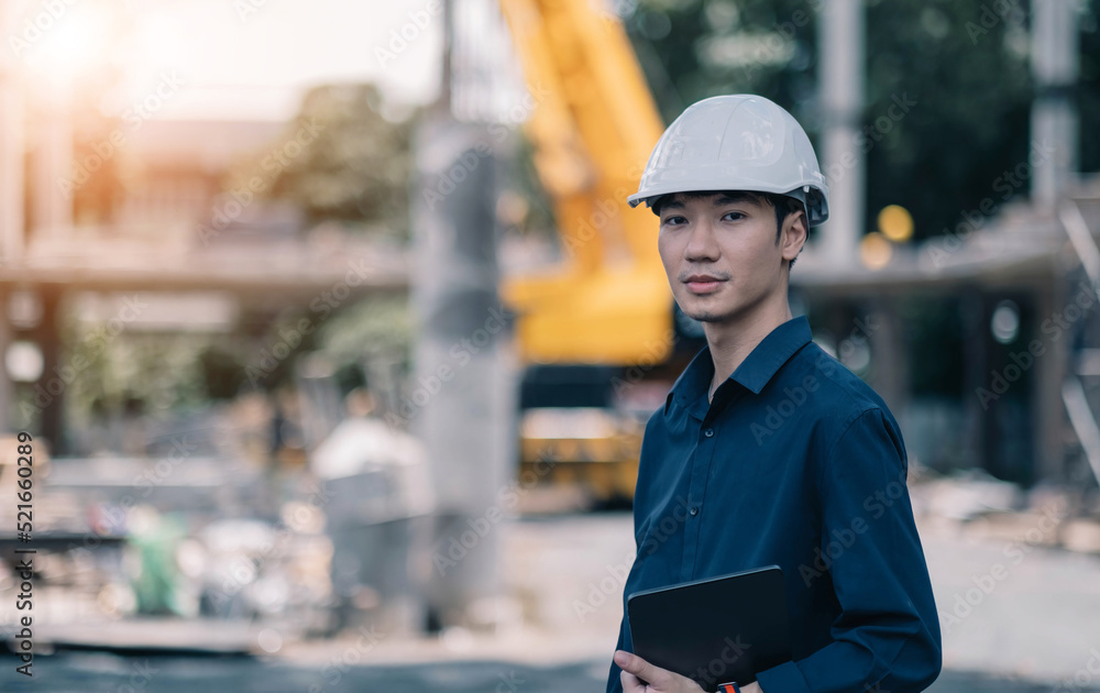 Handsome Male foreman engineer wearing helmet controls and maintains the operation project system.