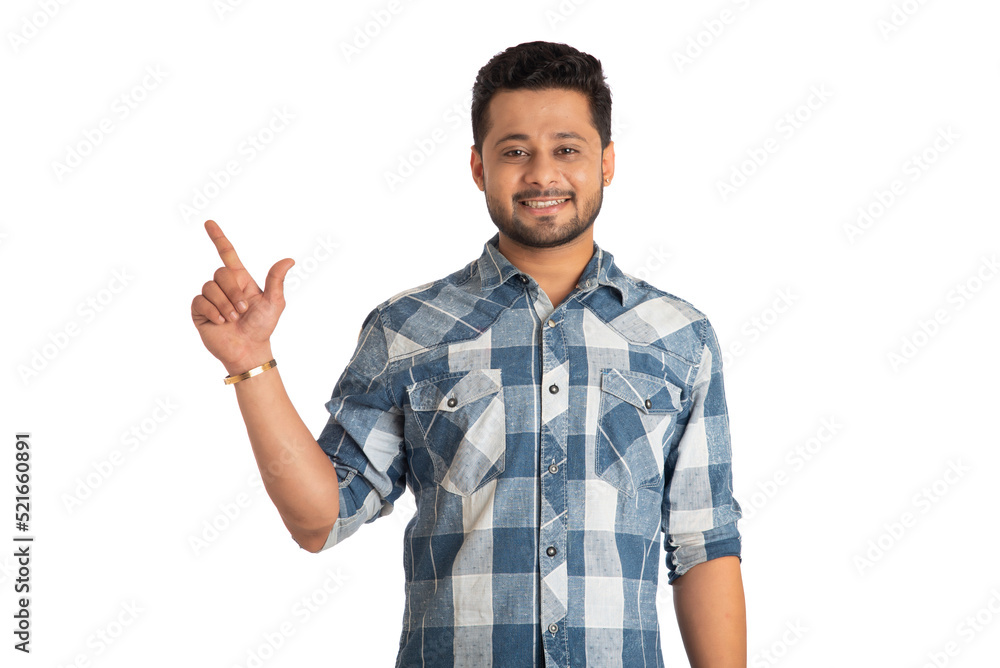 Portrait of a successful cheerful young man pointing and presenting something with hand or finger with a happy smiling face.