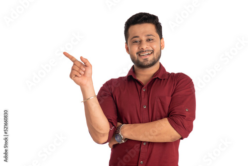 Portrait of a successful cheerful young man pointing and presenting something with hand or finger with a happy smiling face.