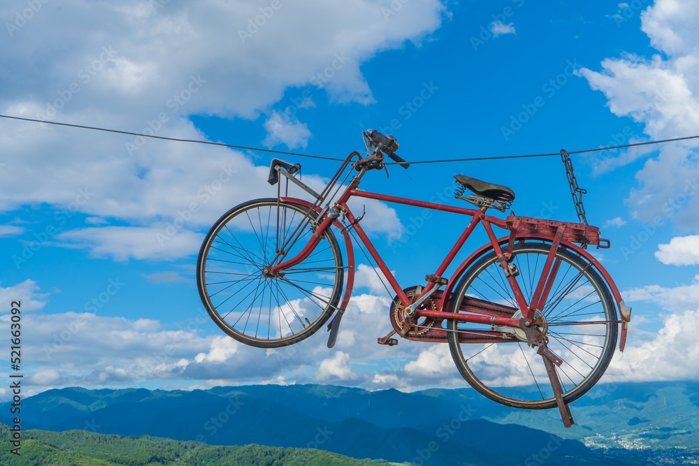 Fototapeta premium 青空の中を飛ぶ、赤い自転車
