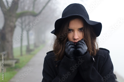Beautiful woman in black clothes walking outdoors in a mist on autumn day © Solid photos