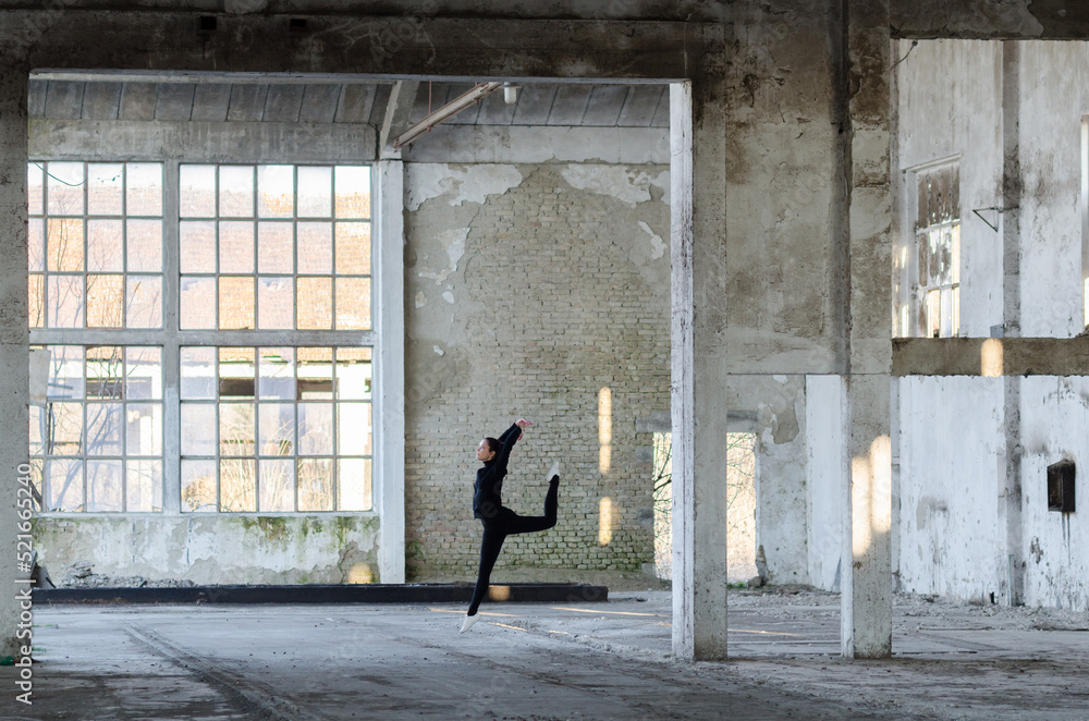 Ballerina jumping and dancing in an abandoned building on a sunny day