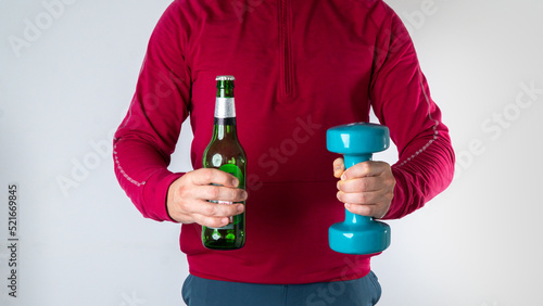 A man makes a choice between a bottle of beer and a workout with dumbbells - choose a sport