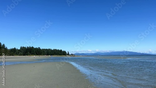 the coast of the Pacific Ocean on Vancouver Island, it can be seen that there was a low tide and now the calm of the wave is barely splashing on the amulet calm silence Rathtrevor Beach, Parksville. photo