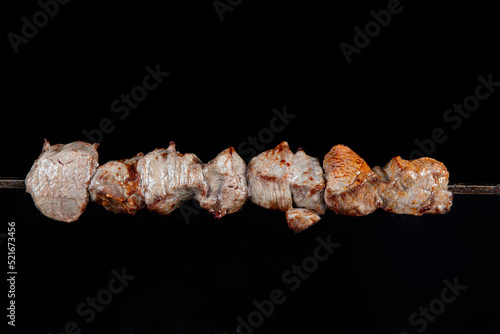 Lamb skewers. Roasted lamb on a skewer. View from above. Metal grilled with delicious meat on black background.