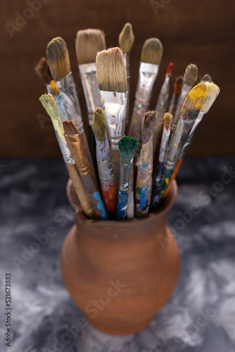 Paint brush in clay jug on table background texture. Paintbrush for painting artistic still life